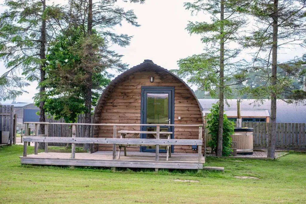 a wooden cabin with a bench in a yard at The Loft by Wigwam Holidays in Kinloss