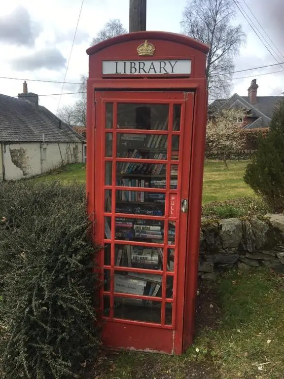 a red phone booth sitting in the grass at Our Log House in the woods in Balnald