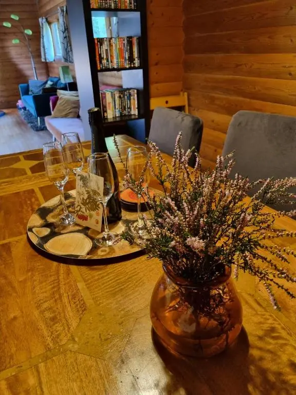 a table with wine glasses and a vase of flowers at Our Log House in the woods in Balnald