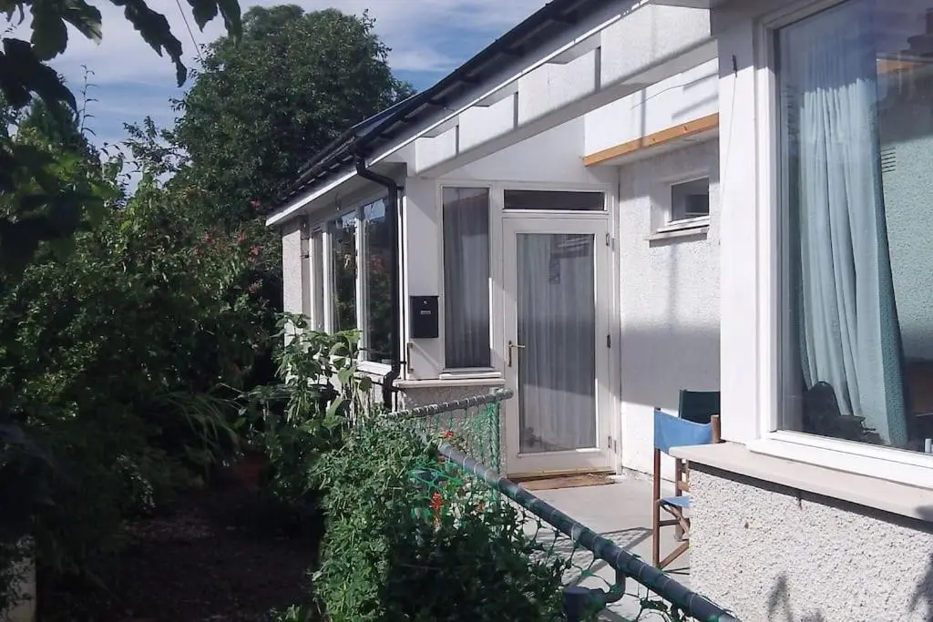 a white house with a door and a balcony at Taigh Sona easy access apartment with double bed in Ullapool