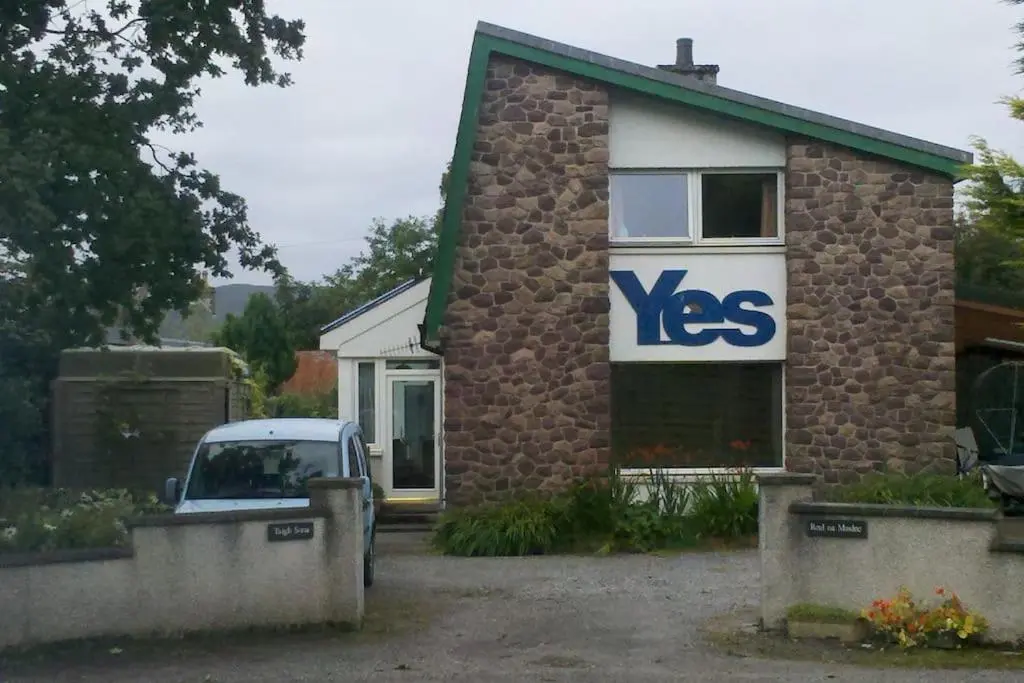 a house with a yes sign on the side of it at Taigh Sona easy access apartment with double bed in Ullapool