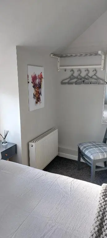 a white bedroom with a bed and a chair at Riverbank Guesthouse Inverness in Inverness