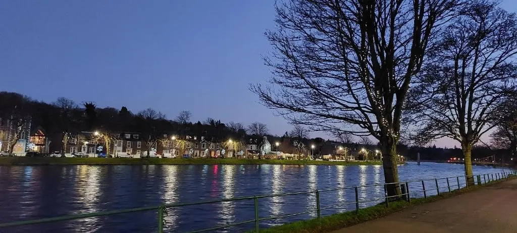 a river at night with houses and a tree at Riverbank Guesthouse Inverness in Inverness