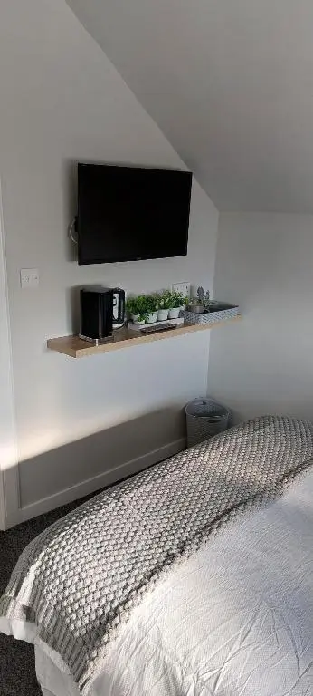 a bedroom with a bed with a tv on the wall at Riverbank Guesthouse Inverness in Inverness