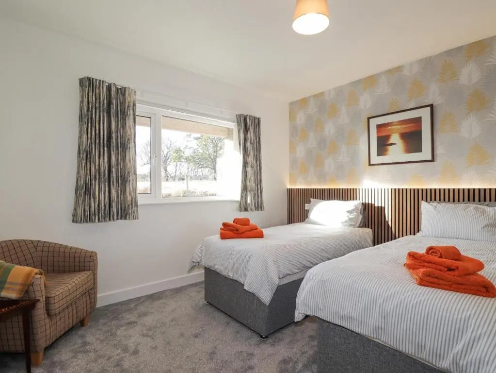 a bedroom with two beds and a chair and a window at Avemar in Buckie