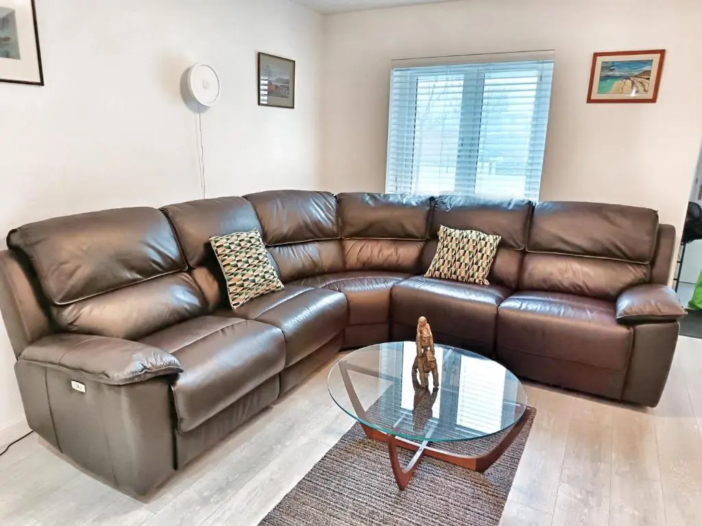 a brown leather couch in a living room with a glass table at 4 miles to Westhill by Lains Lettings in Aberdeen