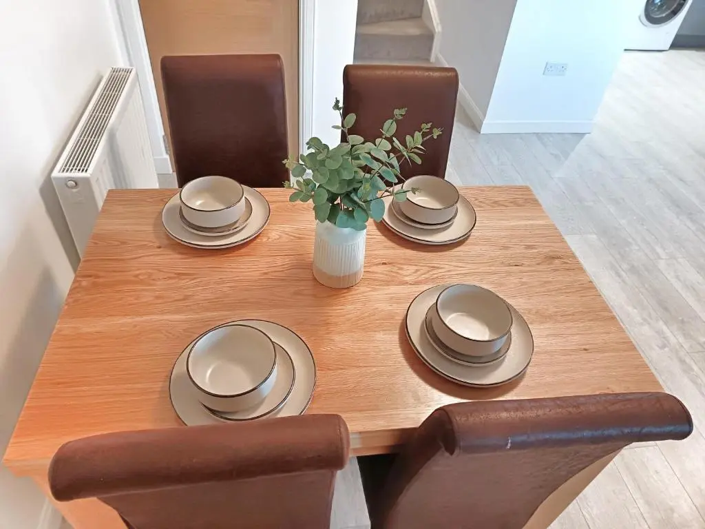 a wooden table with chairs and a vase of flowers at 4 miles to Westhill by Lains Lettings in Aberdeen