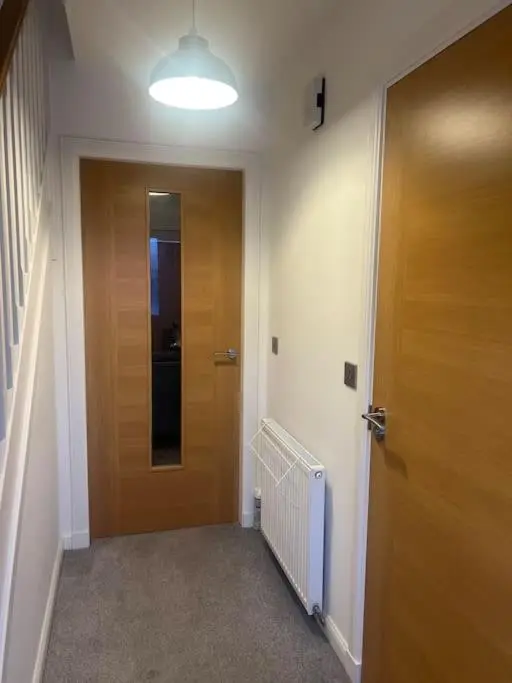 a hallway with a wooden door and a light at Lovely 2 bedroom home, free parking, 6 mins from airport in Bankhead