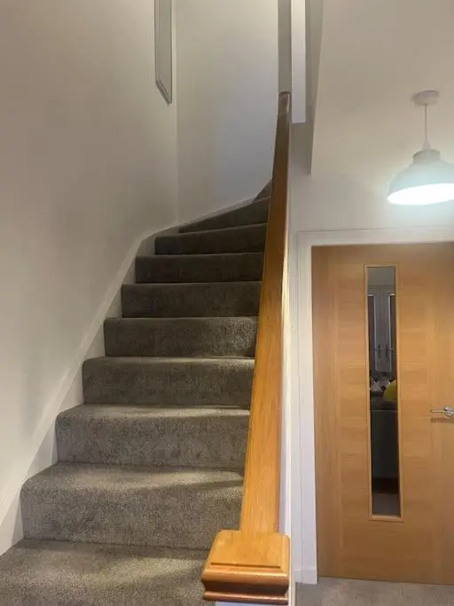 a staircase in a house with a wooden door at Lovely 2 bedroom home, free parking, 6 mins from airport in Bankhead