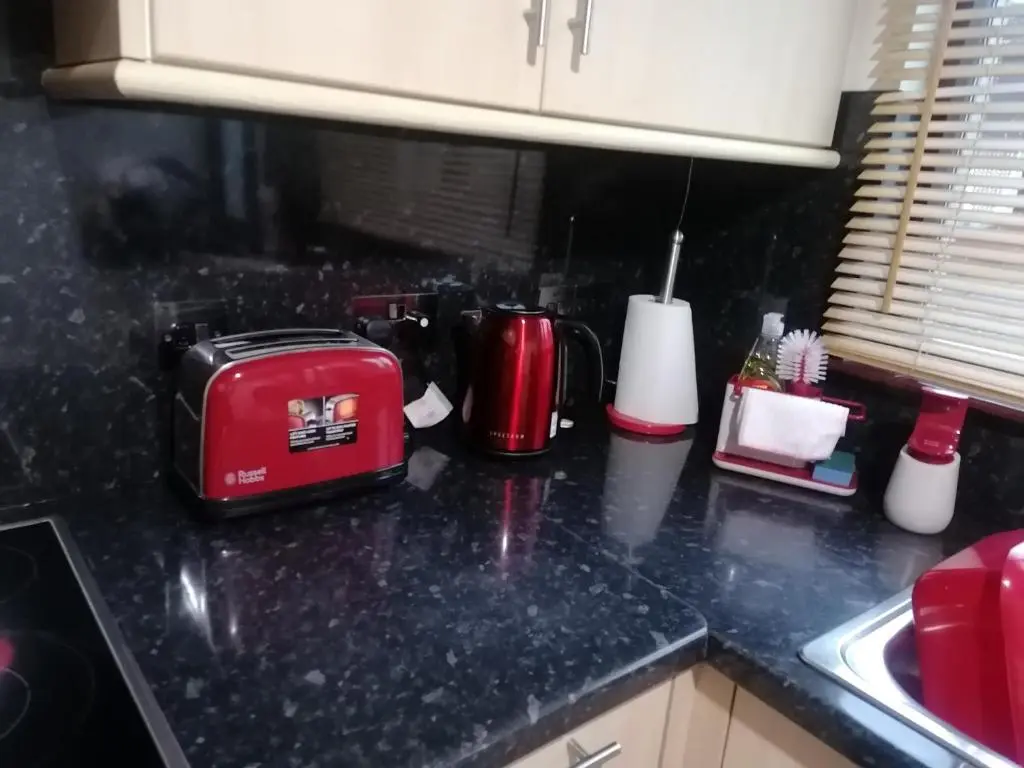 a kitchen counter with a red toaster and a sink at House in Alness in Alness