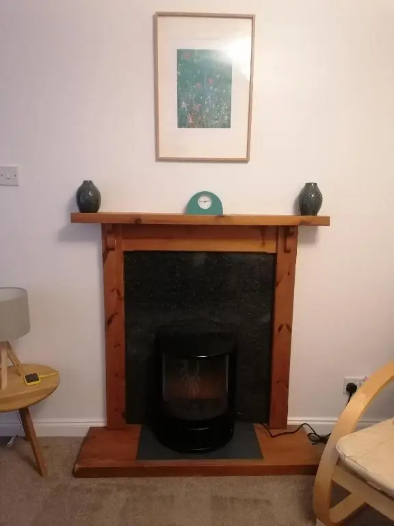a fireplace in a living room with a wooden mantle at House in Alness in Alness