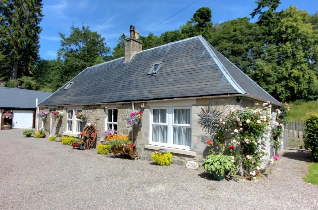 a small house with flowers in front of it at Falls Cottage in Glenlivet