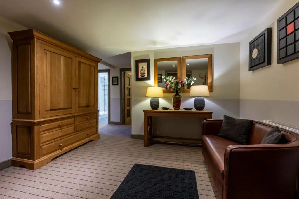 a living room with a couch and a cabinet at Old School Refectory Highland Club in Fort Augustus