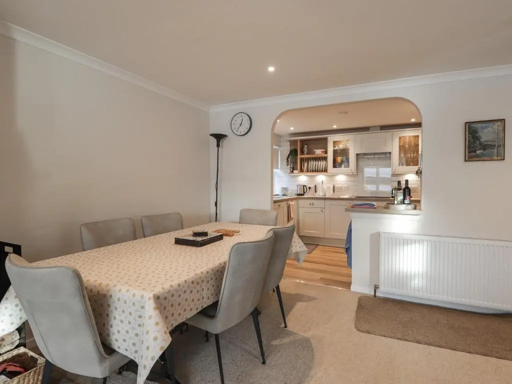 a dining room with a table and a kitchen at Bayside Cottage in Forres