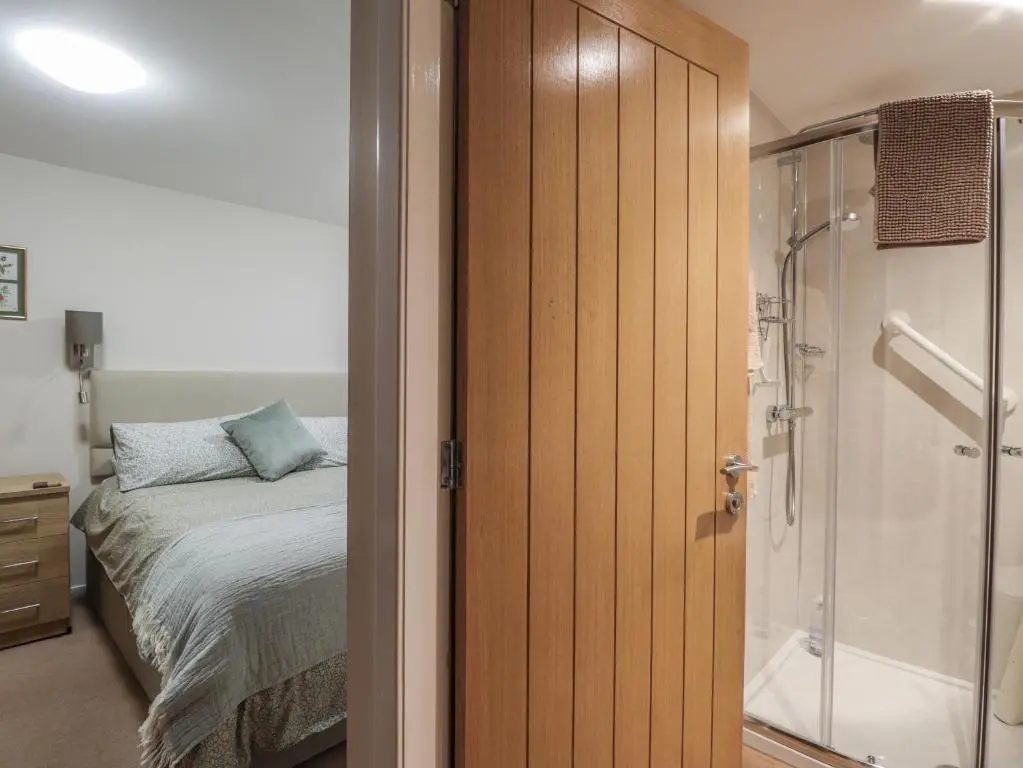 a bedroom with a bed and a glass shower at Bayside Cottage in Forres