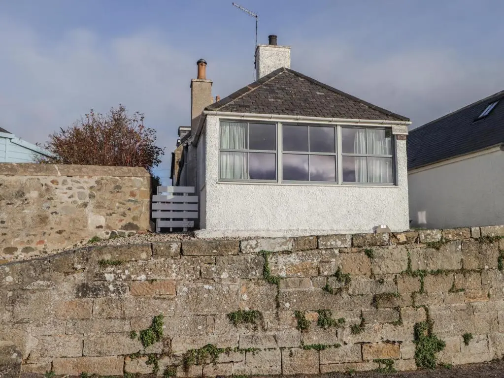a house behind a brick retaining wall at Bayside Cottage in Forres