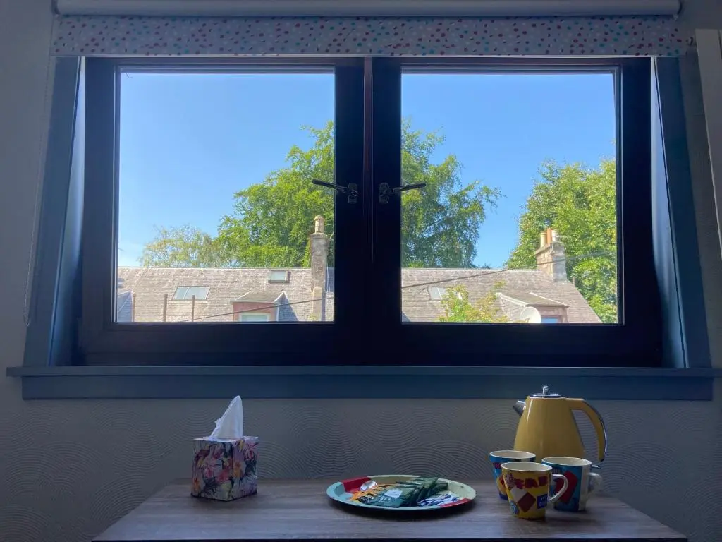 a table with a plate of food and a window at Friars Bridge Guesthouse in Inverness
