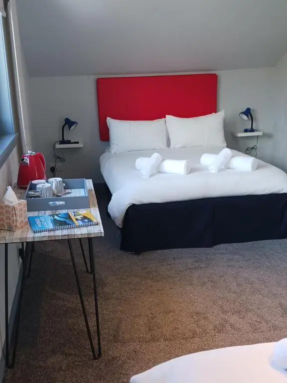 a bedroom with a bed with a red headboard and a table at Friars Bridge Guesthouse in Inverness