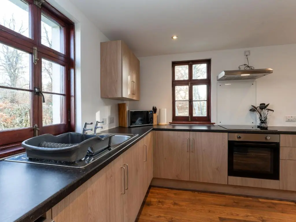 a kitchen with wooden cabinets and a sink at Holiday Home Rose Cottage by Interhome in Farr