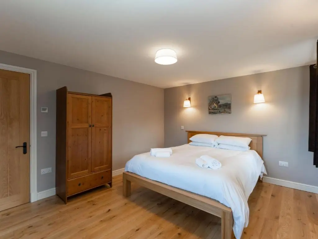 a bedroom with a bed with white sheets and white pillows at Holiday Home Rose Cottage by Interhome in Farr