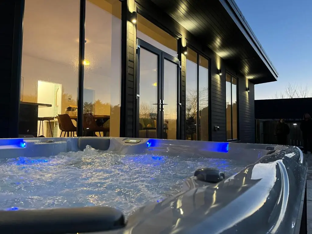 a jacuzzi tub in front of a house at Thrumster Lodges - 3 Luxurious Self Catering Lodges on the NC500, 2 with Hot Tubs in Wick