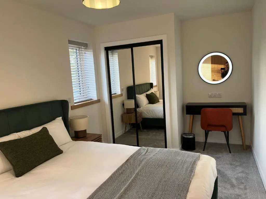 a bedroom with a bed and a mirror and a chair at Thrumster Lodges - 3 Luxurious Self Catering Lodges on the NC500, 2 with Hot Tubs in Wick
