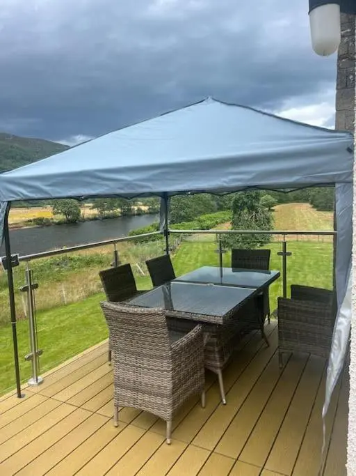a table and chairs on a deck with a blue canopy at Kerrow Burn Lodge Cannich Inverness-shire in Invercannich