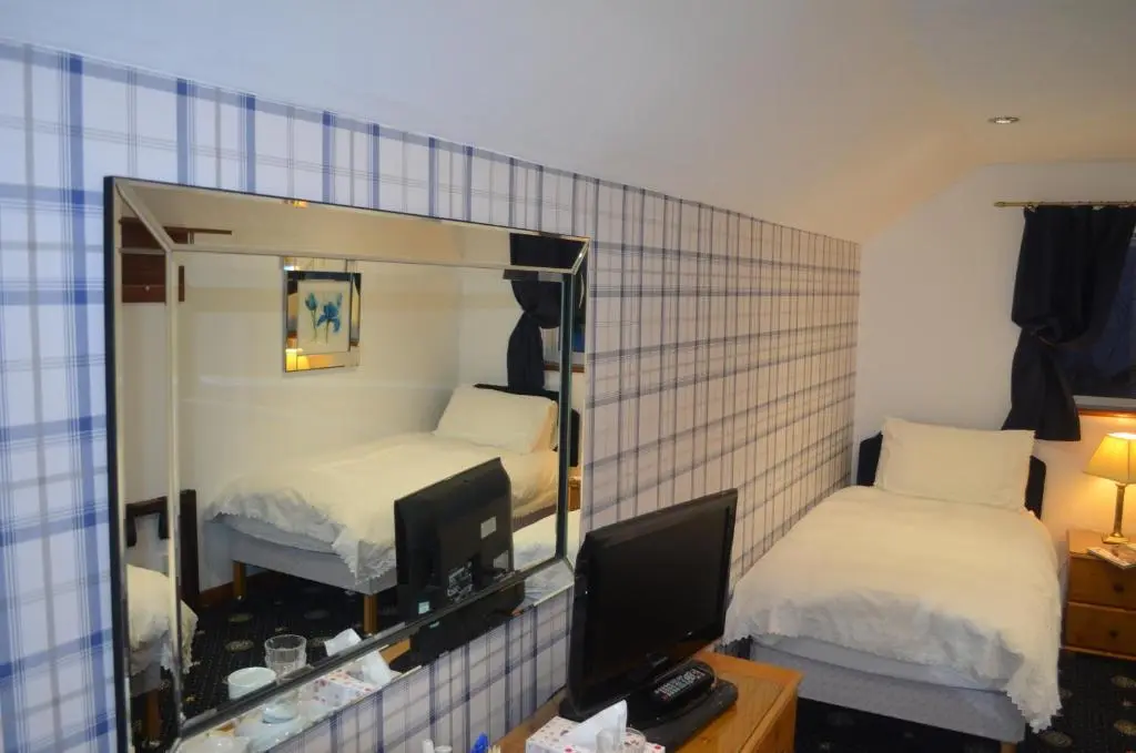 a hotel room with two beds and a mirror at Roseneath Guest House in Inverness