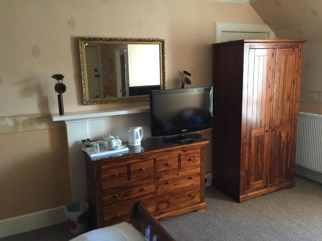 a bedroom with a television on a dresser with a mirror at Roseneath Guest House in Inverness