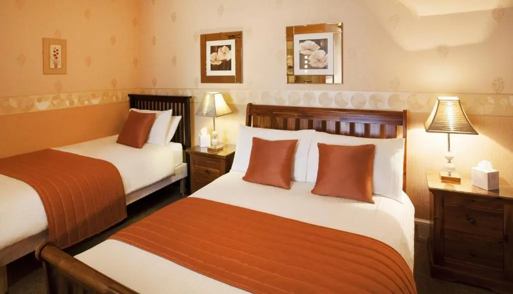 a hotel room with two beds and two lamps at Roseneath Guest House in Inverness