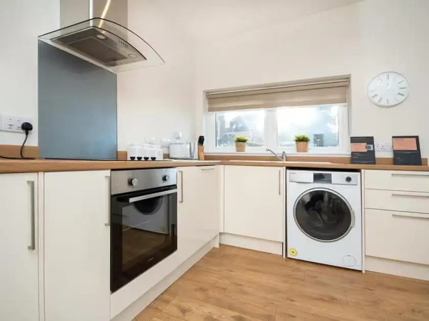 a kitchen with white cabinets and a washer and dryer at View Apartment in Inverness