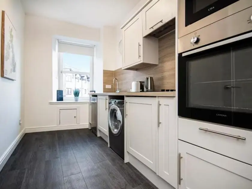a kitchen with white cabinets and a washer and dryer at 4 Lower Kessock Street in Inverness