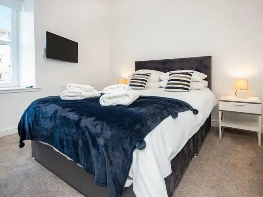 a bedroom with a large bed with towels on it at 4 Lower Kessock Street in Inverness