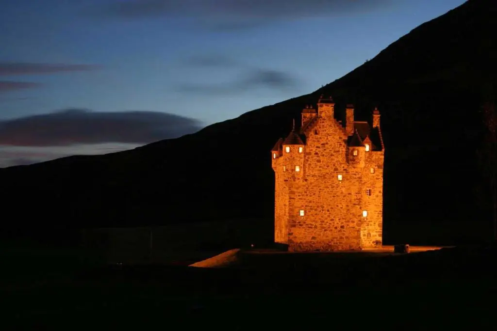 a large castle is lit up at night at Forter Castle in Blairgowrie
