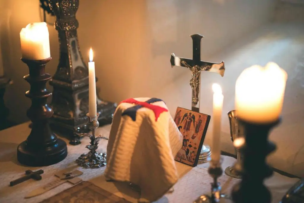 a table with candles and a cross and a towel at Forter Castle in Blairgowrie