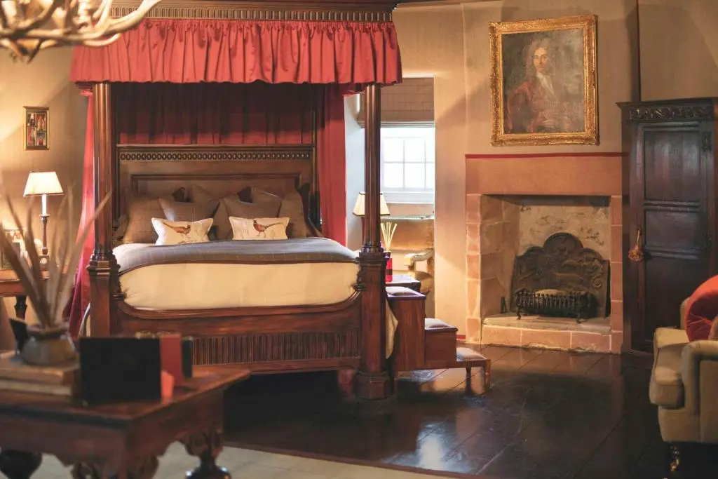 a bedroom with a canopy bed and a fireplace at Forter Castle in Blairgowrie