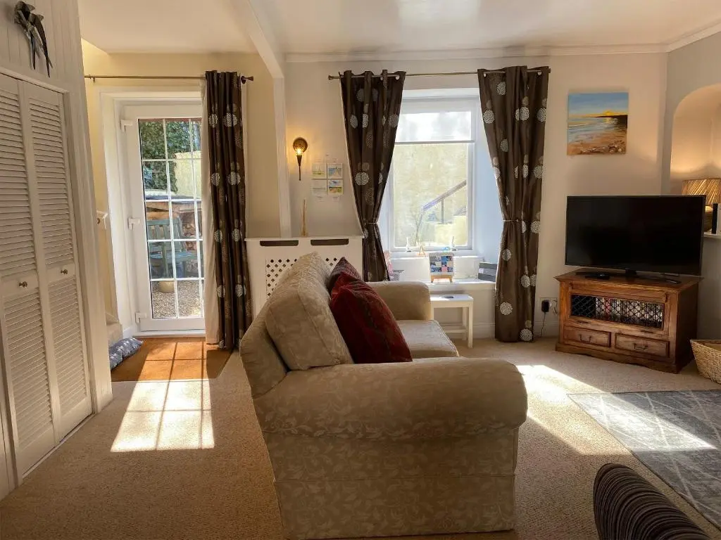 a living room with a couch and a television at Dolphin Cottage in Nairn