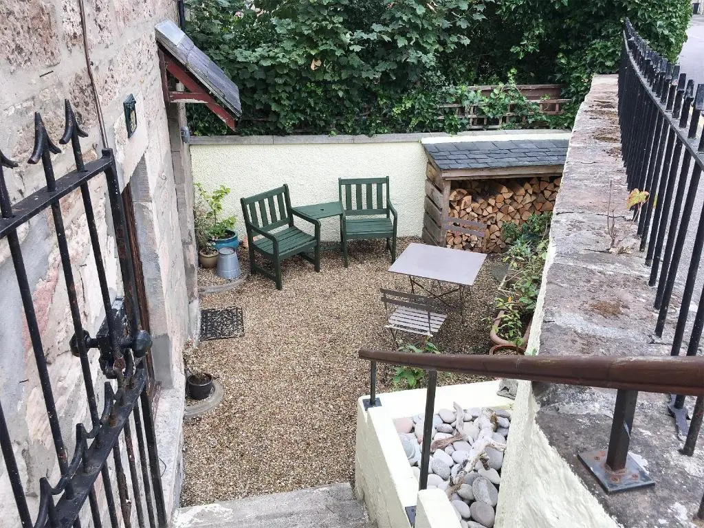a patio with two green chairs and a table at Dolphin Cottage in Nairn