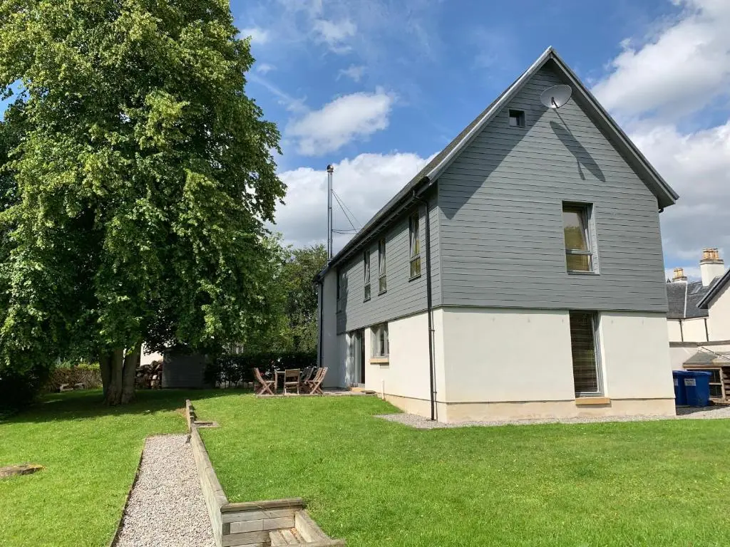 a black and white house with a grass yard at Bright, contemporary house & large private garden in Strathpeffer