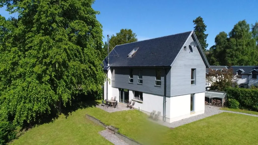 an aerial view of a white house with a black roof at Bright, contemporary house & large private garden in Strathpeffer