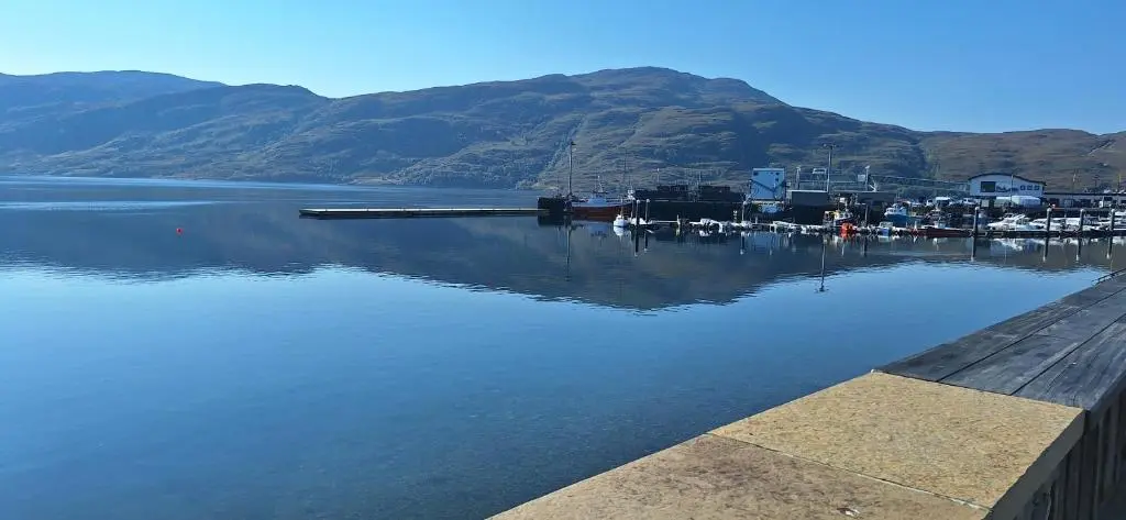 a body of water with a dock with boats in it at CeolMara in Ullapool