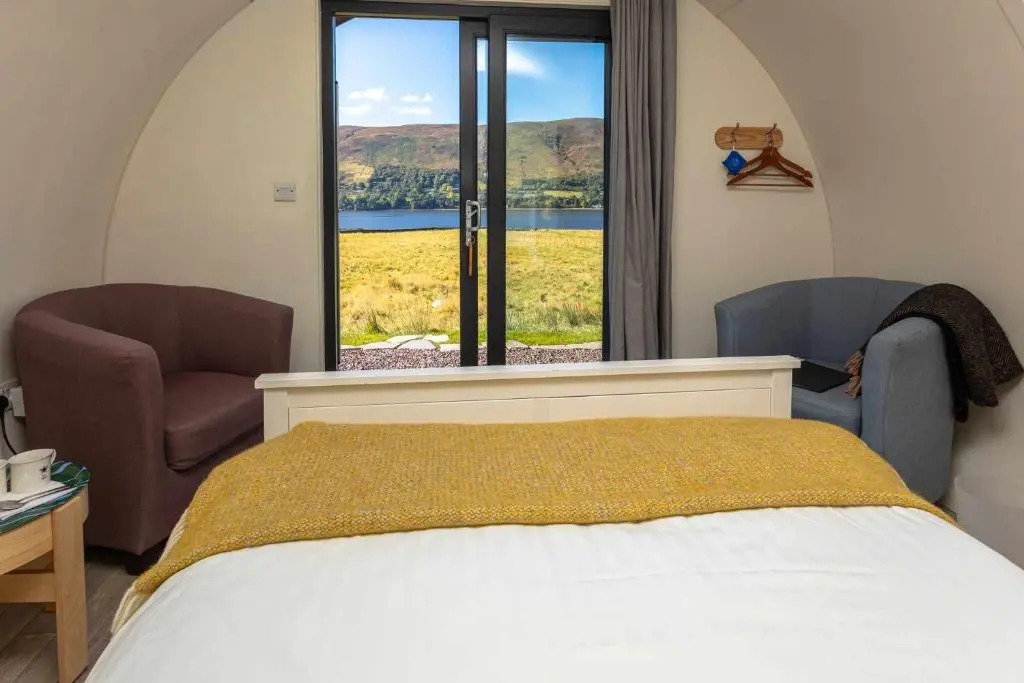 a bedroom with two chairs and a bed and a window at Loch Broom Glamping in Garve