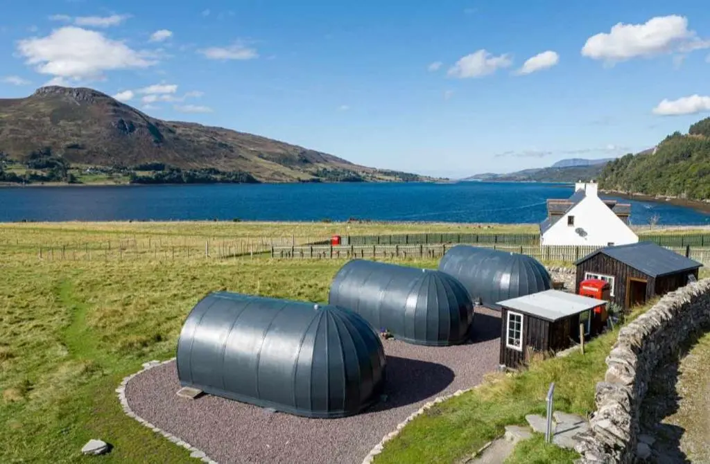 a group of domes in a field next to a lake at Loch Broom Glamping in Garve