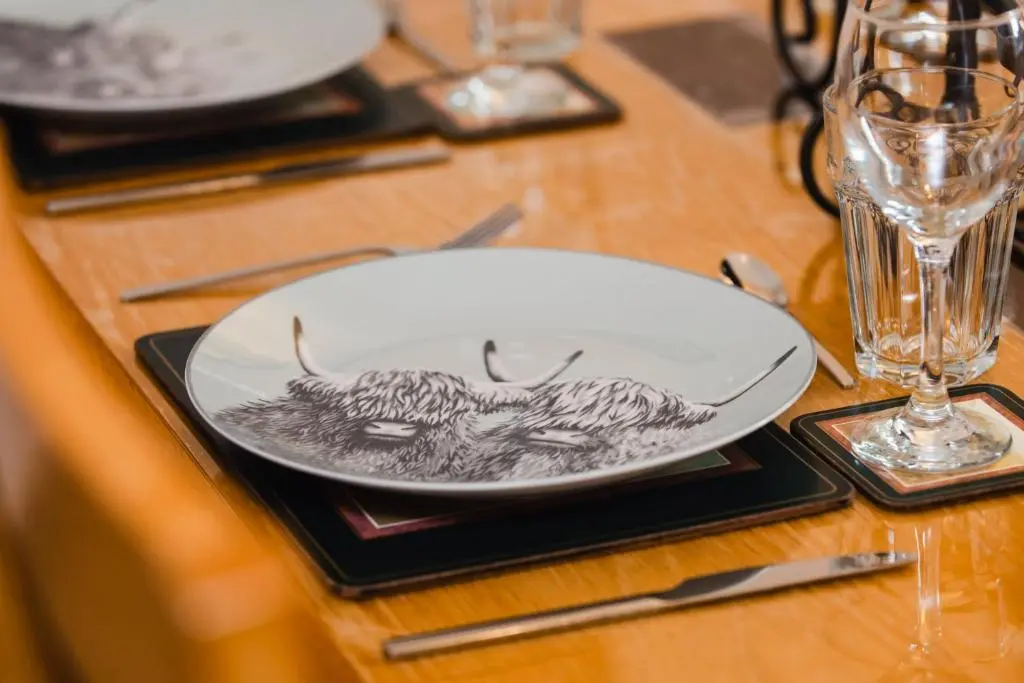 a plate with a drawing of a ram on a table at Traditional Highland Cottage Near Loch Ness in Drumnadrochit