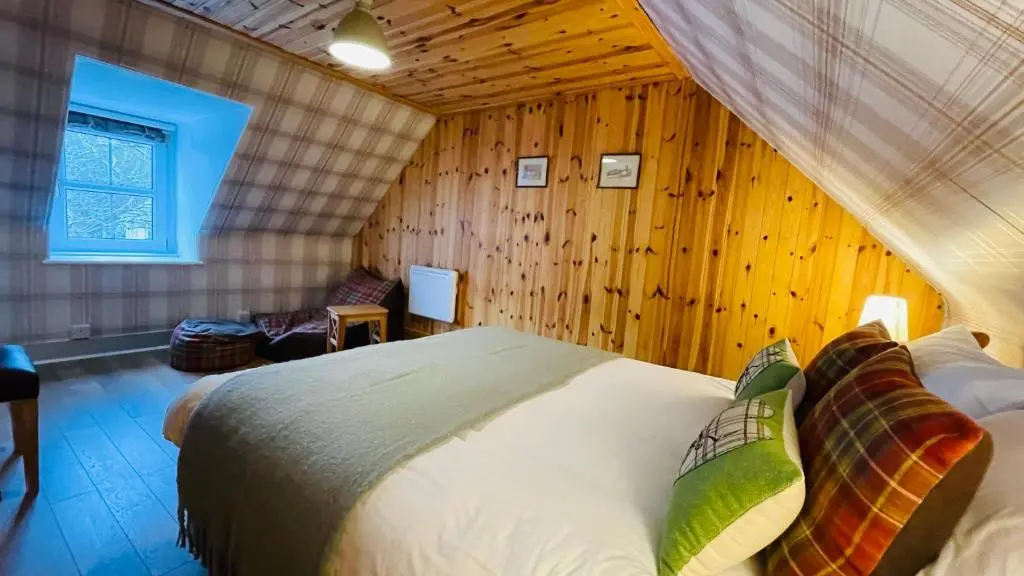 a bedroom with a bed in a room with wooden walls at Traditional Highland Cottage Near Loch Ness in Drumnadrochit