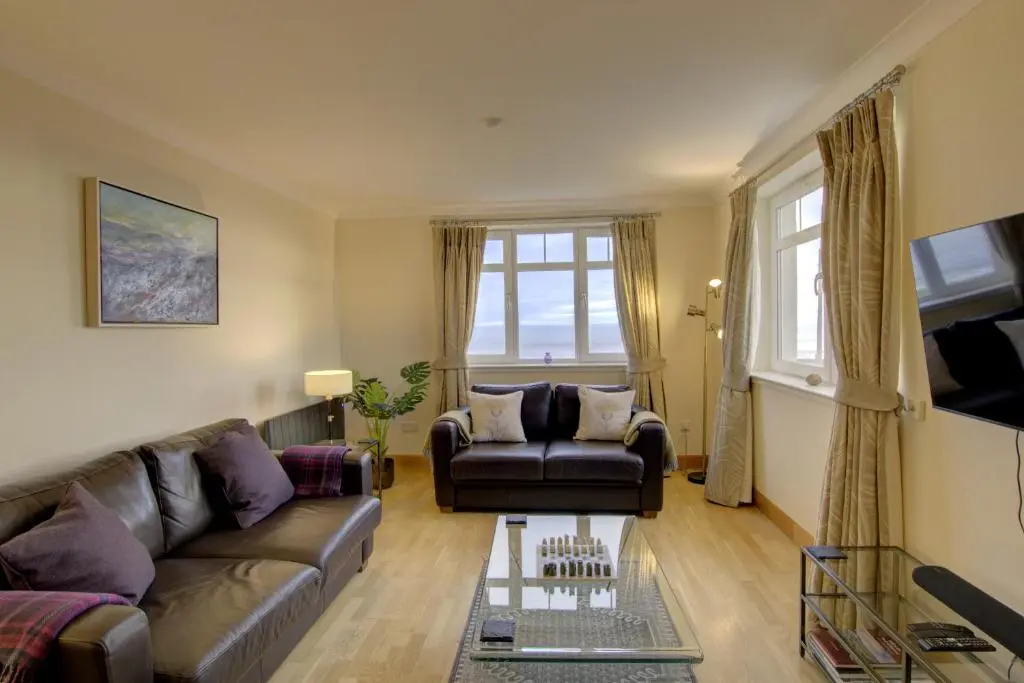 a living room with a couch and a chair at No10 The Links Apartment, Brora in Brora