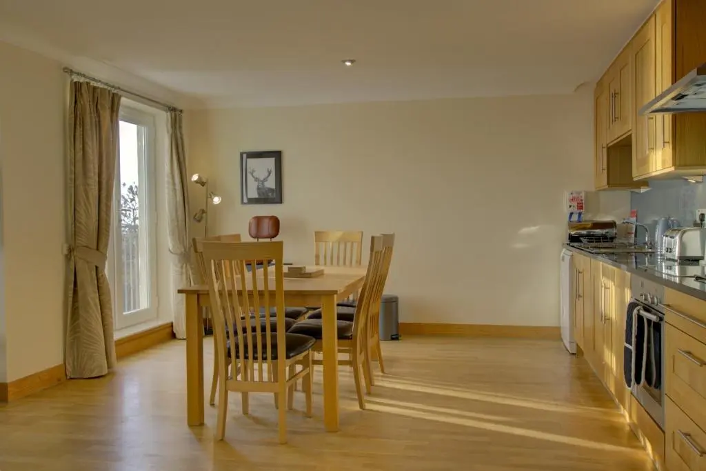 a kitchen with a wooden table and chairs in a kitchen at No10 The Links Apartment, Brora in Brora