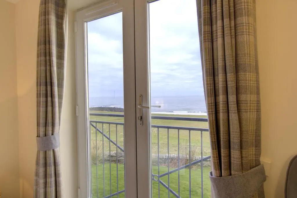 a sliding glass door with a view of the ocean at No10 The Links Apartment, Brora in Brora
