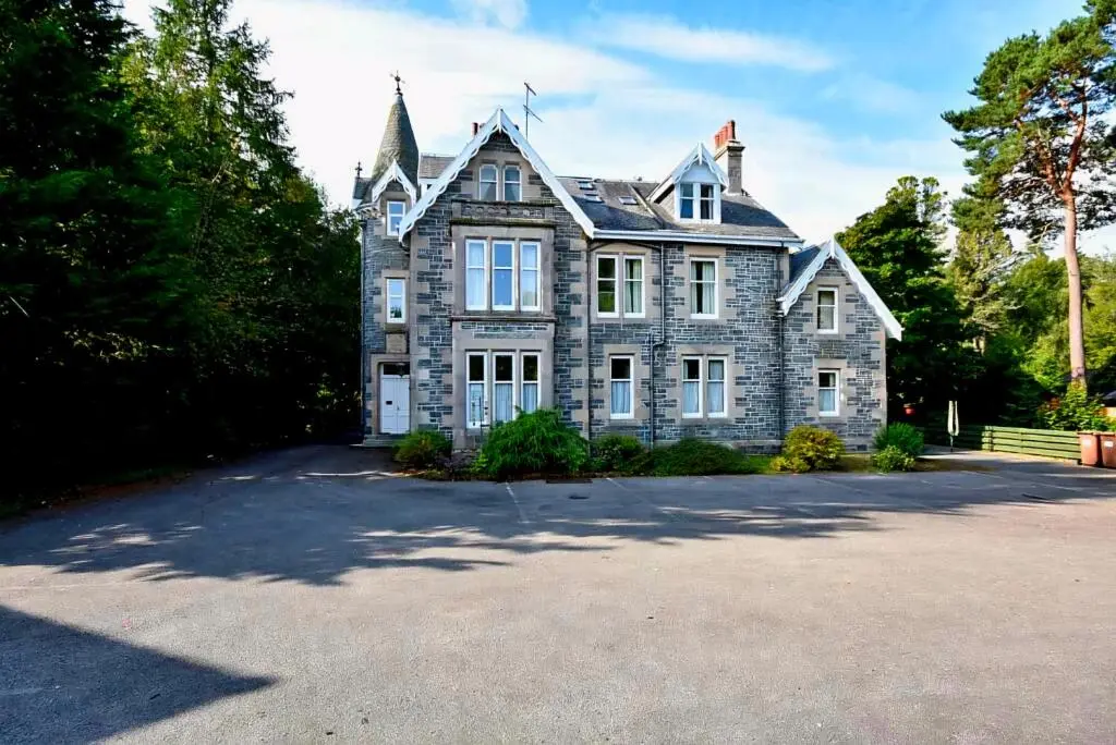a large stone house with a large driveway at Cosy highland getaway in Grantown on Spey
