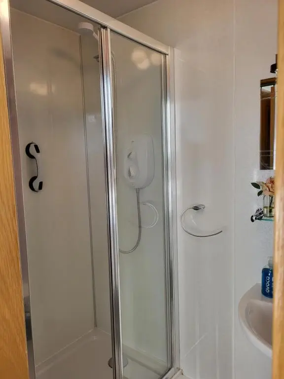 a shower with a glass door next to a sink at Macbeth Arms in Lumphanan